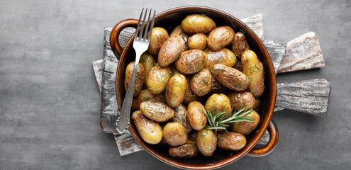Pan filled with roasted potatoes shot on rustic wooden table.