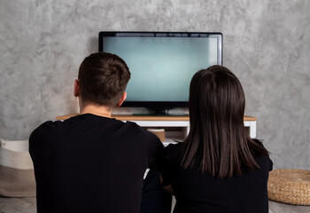 Backs of men and women who are sitting in front of TV. Selective focus. An image for website about...