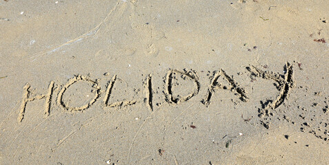large text with the word  HOLIDAY in capital letters on the beach