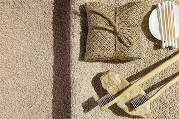 Creative layout made of two toothbrushes, natural soap, cootton buds and pads on sunlit background with towels. Morning routine concept. Top view. Flat lay