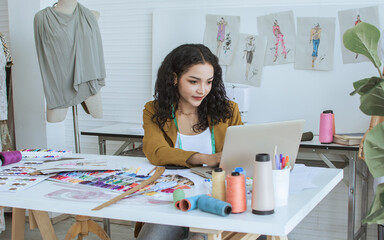 Professional female tailor wearing modern suit, working, using computer for online purchase in...