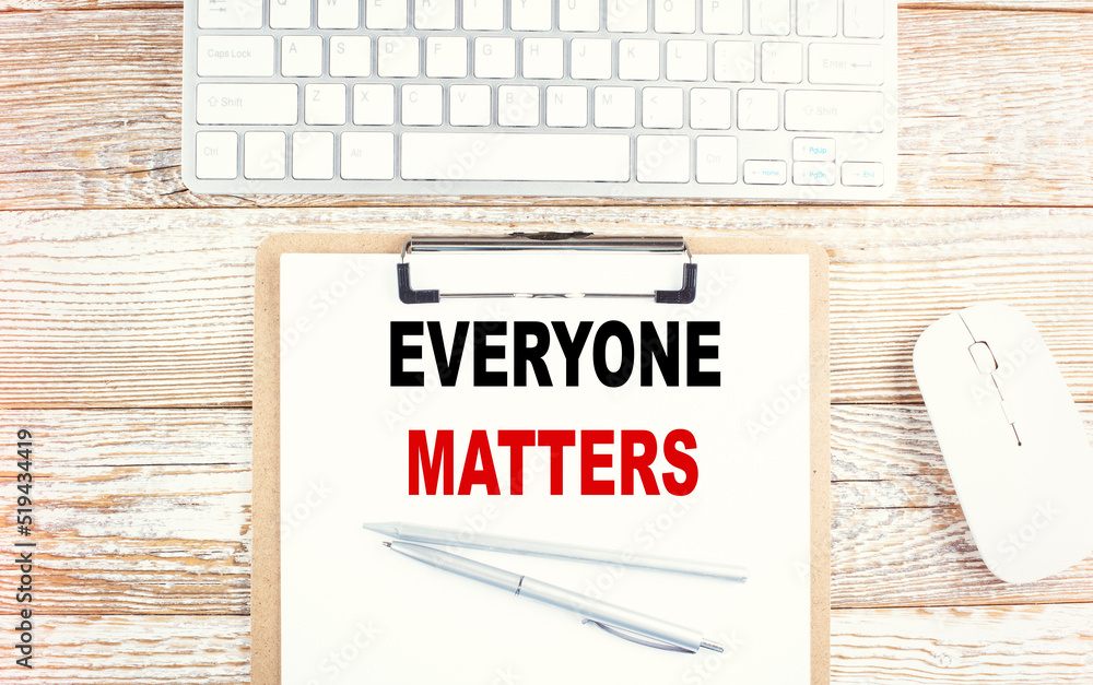 Poster everyone matters text on clipboard with keyboard on wooden background