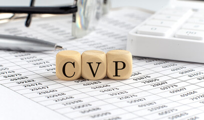 wooden cubes with the word CVP Cost Volume Profit on a financial background with chart, calculator,...