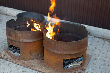 large rusty barrels of coal for roasting on fire