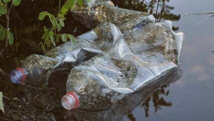 Plastic pollution, used plastic bottles in a pond in the sun. The problem of environmental pollution with plastic waste