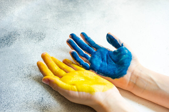 Close-up of a person's hands painted yellow and blue to symbolise support of Ukraine