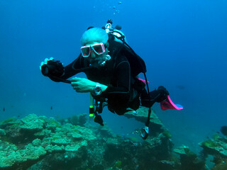 Senior man scuba diving in the Mu Ko Similan National Park and taking a photo, Similan Islands, Thailand