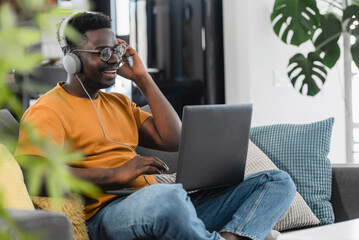 African-American young student man working on a laptop computer at home, listening to an online class, having an online business meeting