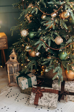 Green Christmas tree with emerald and bronze balls and craft gift boxes on the floor. Christmas interior on a postcard. Close-up