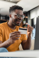 A young black cheerful man paying online with credit card