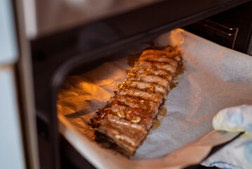 the girl takes out the baked pork ribs from the oven