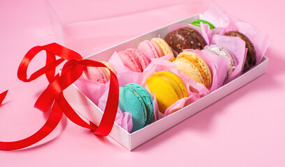Colorful sweet macarons or macaroons, flavored cookies are in the paper box on the pink background