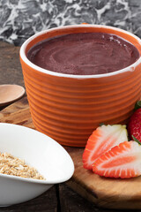 Traditional açaí in a bowl served with granola and strawberry. Selective focus.
