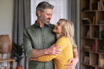 Romantic Middle Aged Couple Embracing At Home And Smiling To Each Other