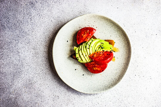 Overhead view of a slice of avocado toast with tomato and sesame seeds