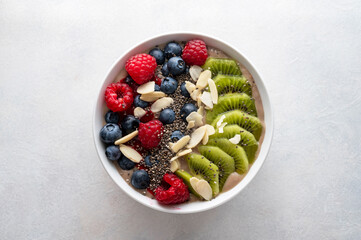 Smoothie bowl with fresh berries, kiwi, oats, chia seeds. Breakfast healthy meal, bright background