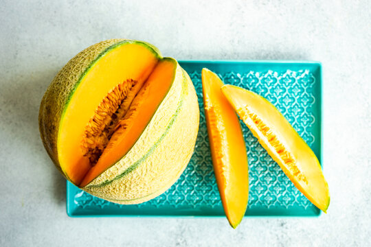 Overhead view of a cantaloupe melon and slices of melon on a plate