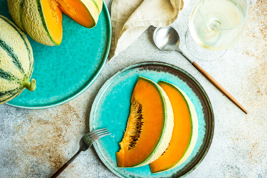 Overhead view of cantaloupe melons, slices of melon and a glass of white wine