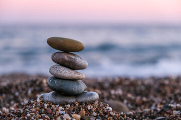 Fototapeta na wymiar Selective Focus, focused on foreground, pyramid of pebbles on the beach at sunset. Concept of zen, stability, harmony, balance and meditation, copy space. 