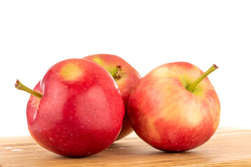 Three red sweet apples on a kitchen board, close-up, on a white background.
