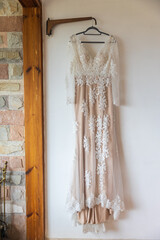 long white and pink bridesmaid dress with embroidery and sequins is on a hanger on the wall