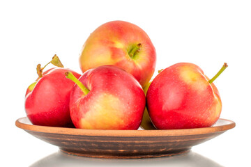 Several ripe sweet red apples on a clay dish, close-up, isolated on a white background