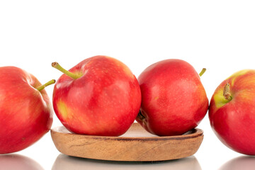 Several ripe sweet red apples with a wooden saucer, close-up isolated on a white background.