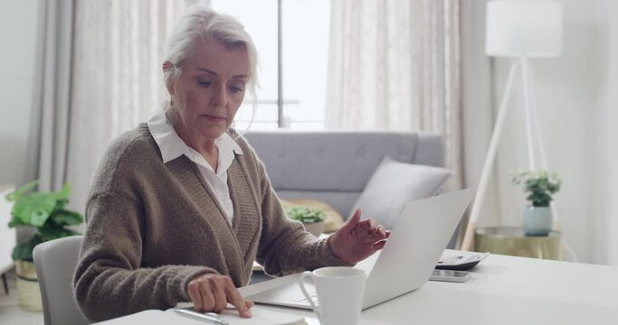 Old Author writing a book on a laptop sipping some tea or coffee at home. A senior female writer typing her life story and sharing her creative hobby. An old lady drafting a journal in her house