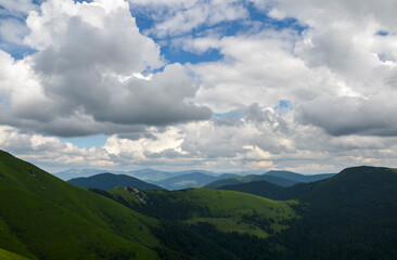Beautiful panoramic view of highland to green mountain hills with forest landscape with cloudy blue sky. Carpathian Mountains, Ukraine