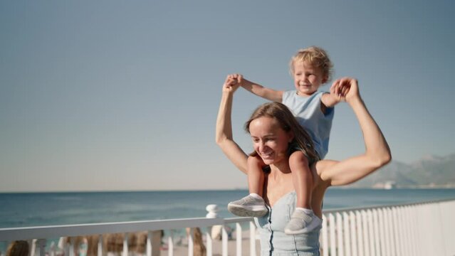Young beautiful mother holds a 2 year old sweet son. Walk in the summer at the beach . carries on the shoulders a close-upHigh quality 4k footage