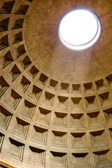 The Pantheon Dome in Rome, Italy as the light shines through the oculus a central opening in the roof is a classic architectural design from the Roman Empire rebuilt by Emperor Hadrian.  