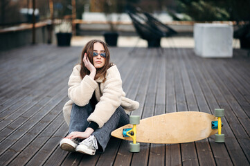 Female hipster sitting on rooftop near skateboard