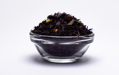 black tea with flowers and pieces of fruit in a glass bowl on a white background