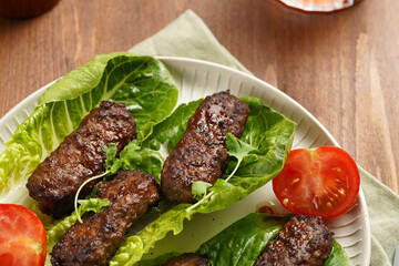 Traditional south european skinless sausages cevapcici made of ground meat and spices on lettuce...