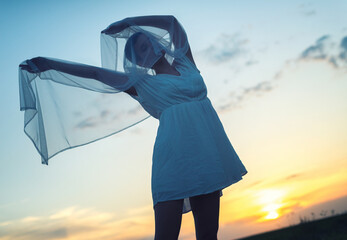 Beautiful young woman dancing with veil during summer sunset