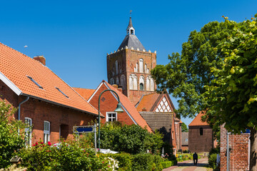 Dorfstraße in Pilsum mit Blick auf die Kreuzkirche St. Stephanus; Ostfriesland; Deutschland