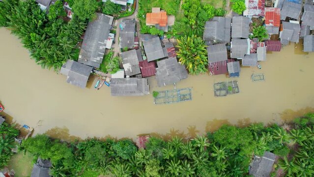 An aerial view over a fishing village by a canal in the countryside in Chumphon Province, Thailand. Crab trapping in the canal. canoe. Palm and coconut groves. 4k
