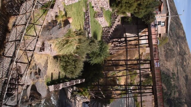 moving river under distant metal bridge with trees, checacupe, cusco, peru