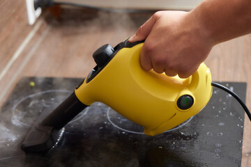 Cleaning of induction cooker with steam cleaner.
