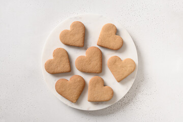 Heart shaped cookies on white marble plate on white background. View from above.