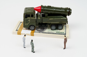 On the dollars is a toy military vehicle, next to the figures of businessmen.
