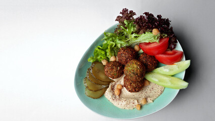 Arabian meal, hummus and falafel with fresh vegetables. On a white background