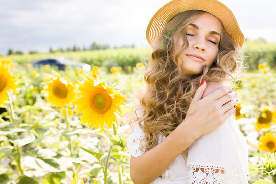 Young blonde girl with long curly hair in a field of sunflowers
