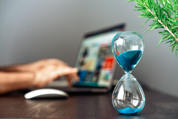 Hourglass with blue sand on the desk