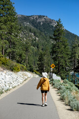 Woman is hiking on a trail at Lake Tahoe with a view of mountain and lake.