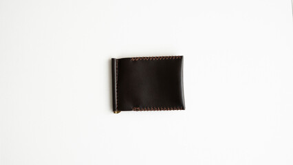 Brown men's money clip handmade leather wallet. Empty money clip wallet with a two pockets for cards lies on a white table. Selective focus, copy space.