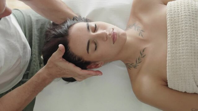 top view of a therapist with his hands on the forehead of a young woman in Reiki therapy.