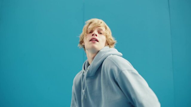 Young man dancing hip hop. Modern dance choreography. Professional breakdancer training on blue background, dancer showing dance movings outdoor. Musical video.