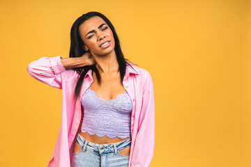 Tired upset african american woman massaging hurt stiff neck isolated over yellow background, fatigued sad black lady rubbing tensed muscles to relieve joint shoulder pain, fibromyalgia concept.