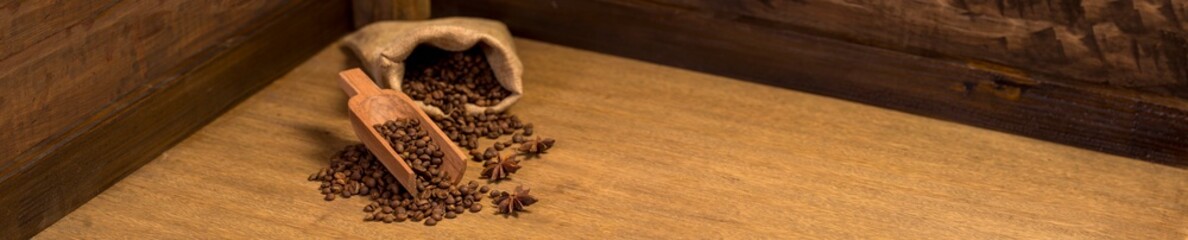 bag and coffee shovel full of coffee beans on wooden background. panoramic image with copy space.